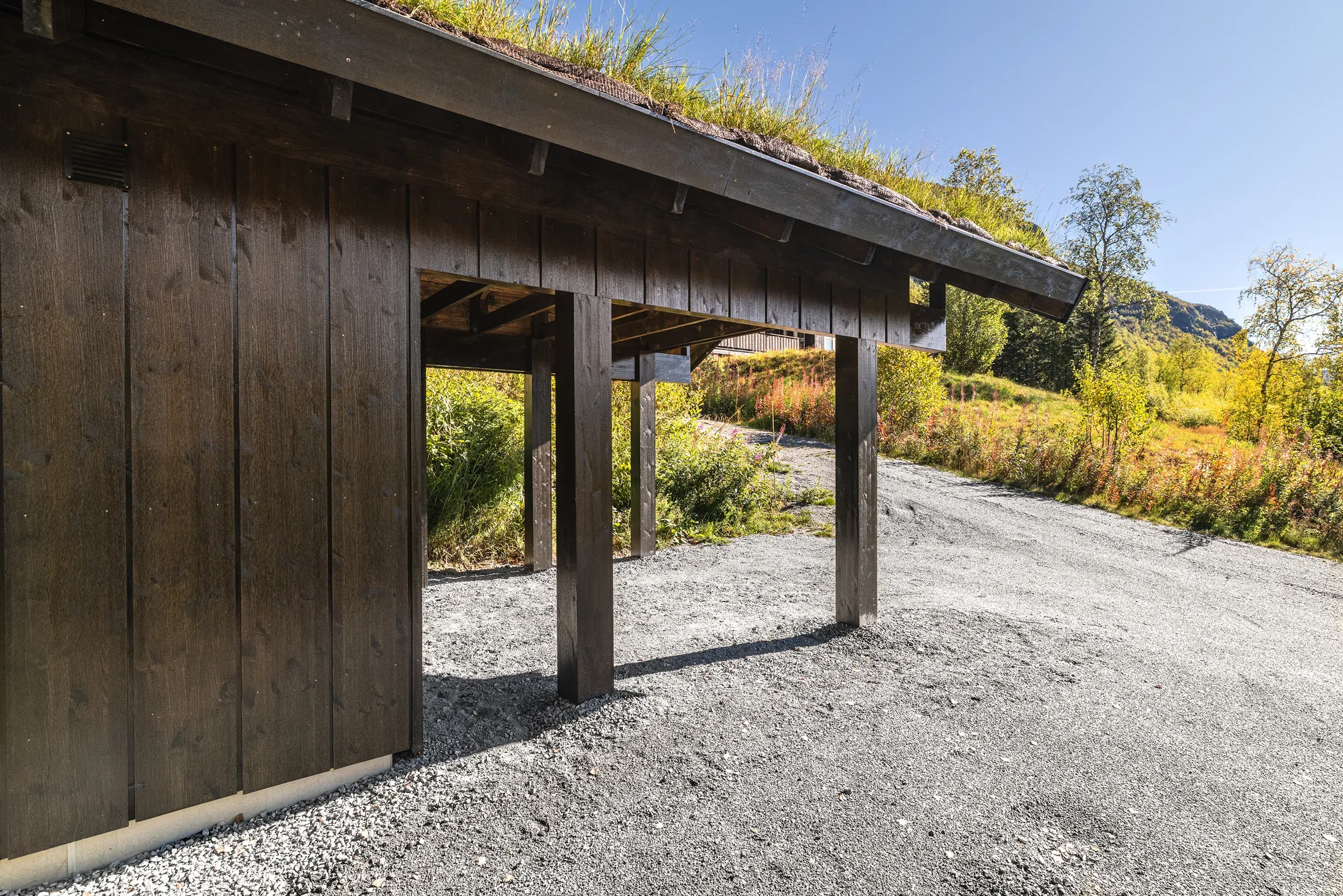 Carporten sett fra siden med stående kledning og torvtak