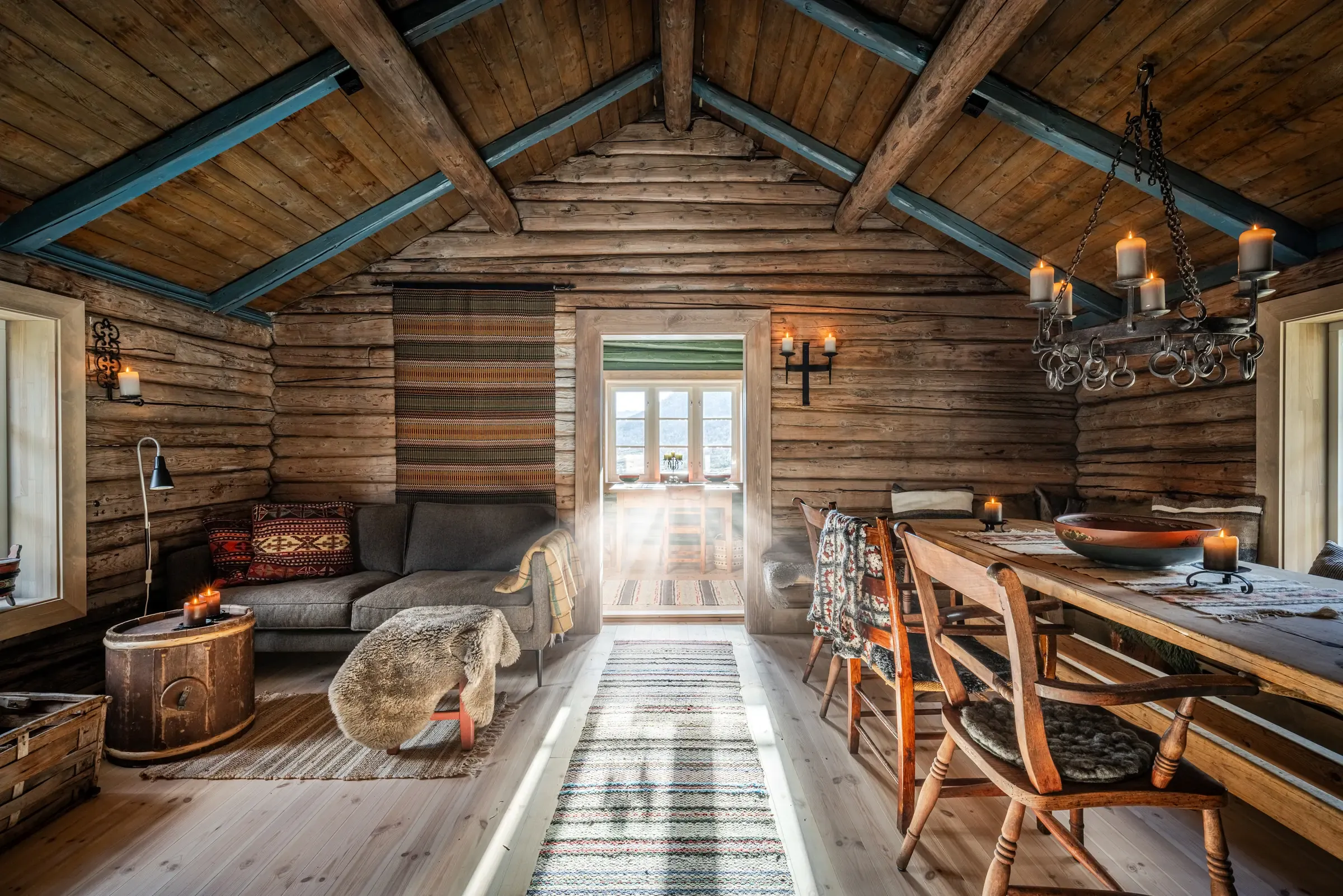 Living room in the restored farmhouse with old log walls and exposed roof beams